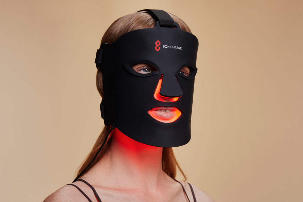 Woman wearing the Bon Charge mask with a warm red glow across her face